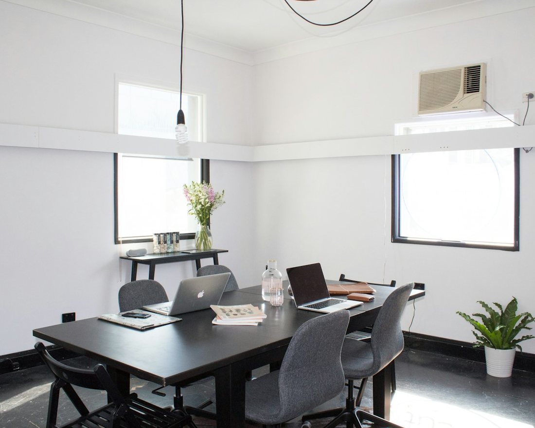 Small meeting room with a work table, laptops and a wall-mounted air conditioner