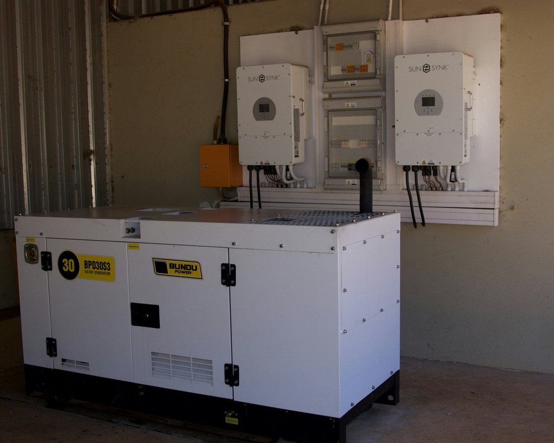 White silent diesel generator with solar inverters and distribution boards in a power backup room